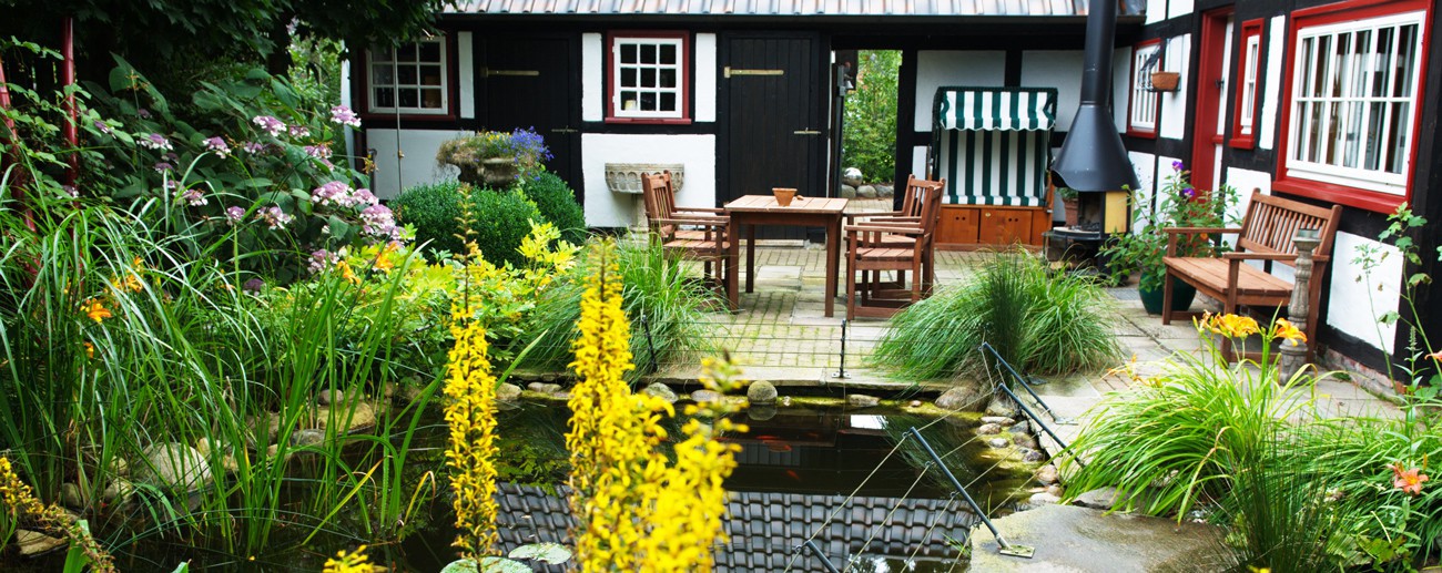 Wohnlicher Garten mit Terrasse, Pflanzflächen und einem kleinen Wasserbecken