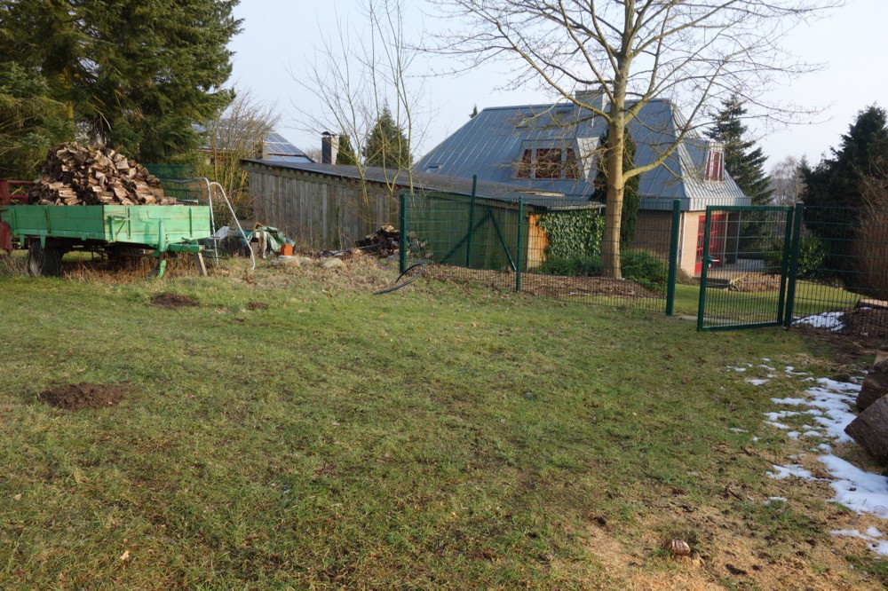 Weitläufige Rasenfläche mit Einzäunung vor Beginn der Gartenarbeiten