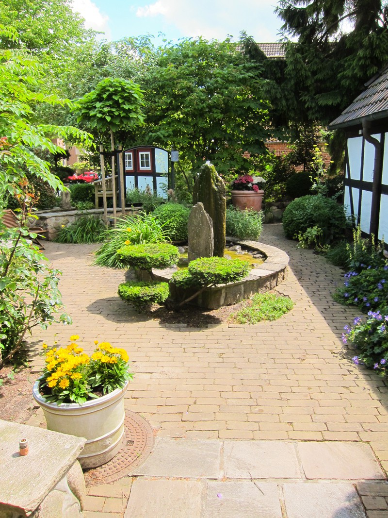 Verwunschener Weg mit Formgehölzen und Wasserspiel im Bürogarten von Eskildsen Gärten
